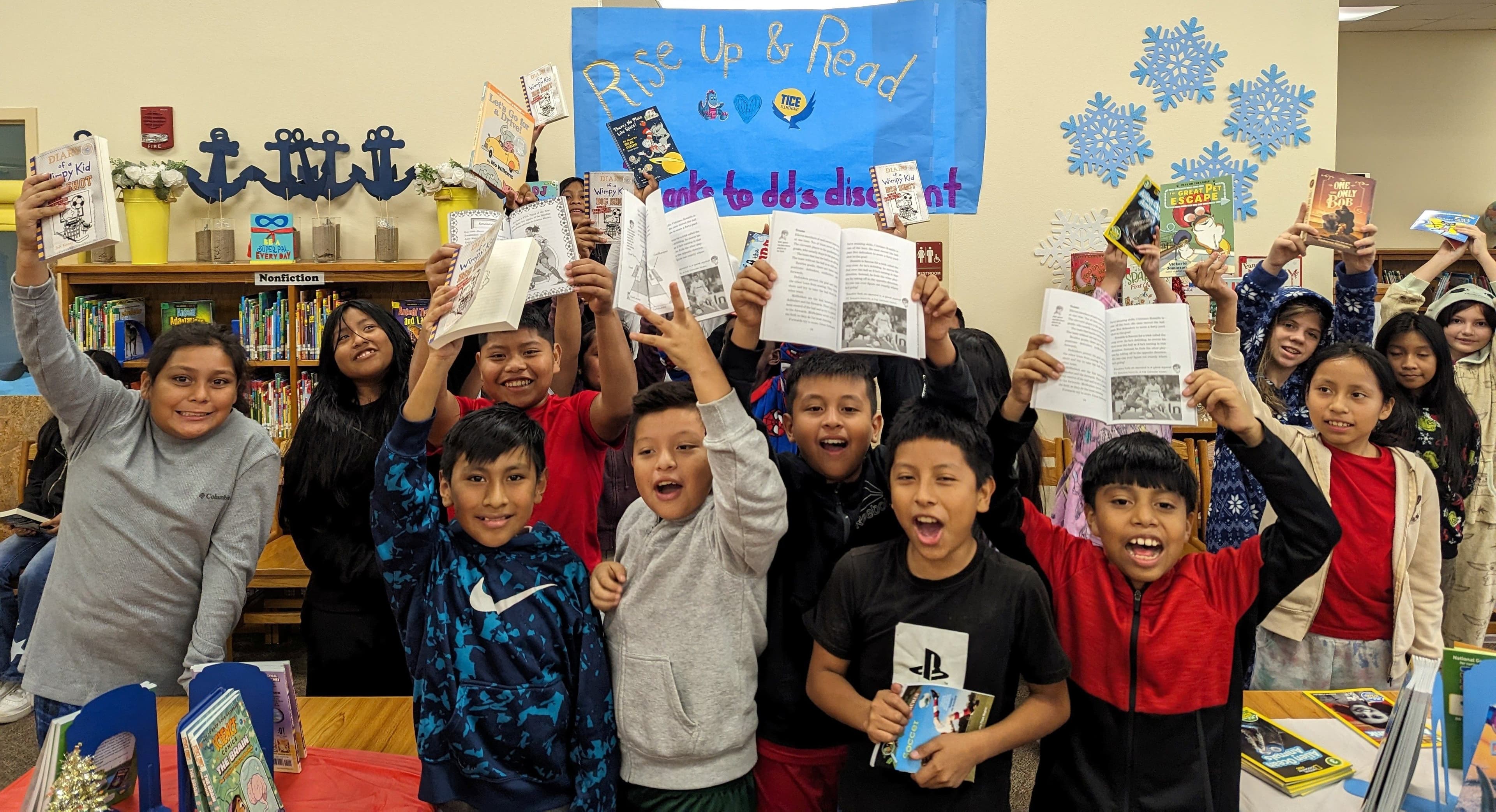 Children holding up books in a classroom